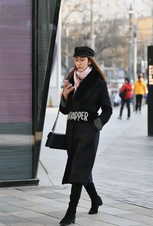 街拍美女搭配浅粉色羽绒服,一双平底短靴,把手放在脸颊很可爱